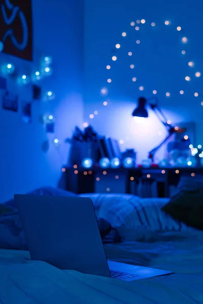 Крупный План Ноутбука Кровати Темной Комнате Украшенной Синими Неоновыми Лампами — стоковое фото