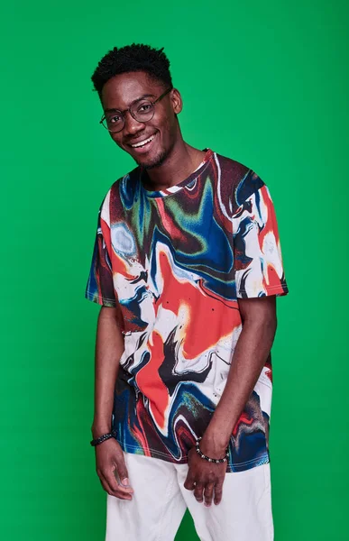 stock image Portrait of African teenage boy in bright shirt smiling at camera posing against green background