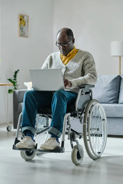 Африканский Человек Ограниченными Возможностями Сидит Инвалидной Коляске Печатает Ноутбуке Комнате — стоковое фото