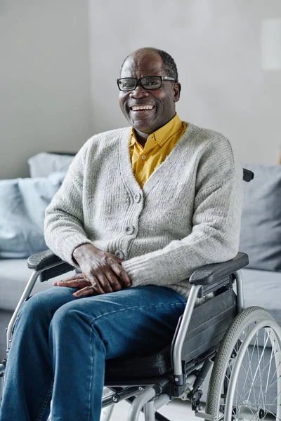 車椅子に座ってカメラに向かって笑っているアフリカの成熟した男の肖像画 彼は自宅で休んでいる — ストック写真