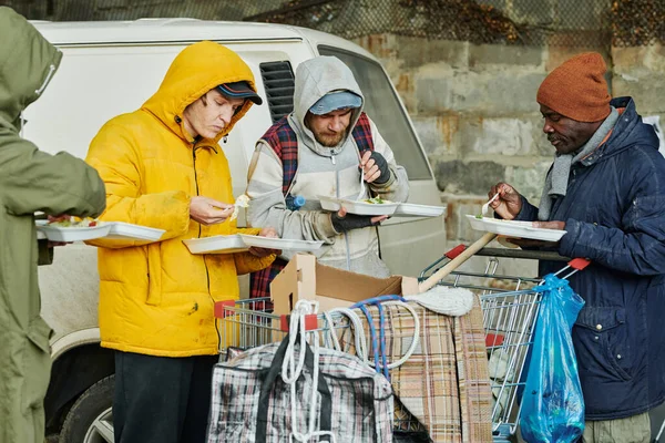 ホームレスの人々が屋外で一緒に熱い食べ物を食べ 慈善団体から食べ物を得る — ストック写真