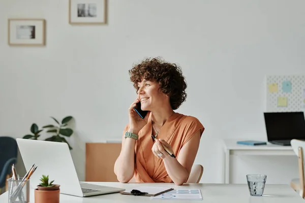 Jovem Empresária Conversando Celular Sorrindo Enquanto Senta Seu Local Trabalho — Fotografia de Stock