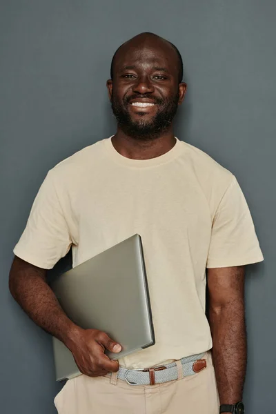 アフリカの若いビジネスマンの肖像は 灰色の背景にラップトップで立ってカメラで微笑んだ — ストック写真