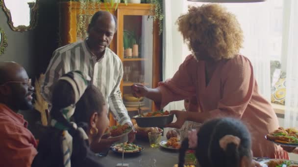 家族の夕食時にゲストのために食べ物を提供するもてなしのアフリカ系アメリカ人女性 — ストック動画