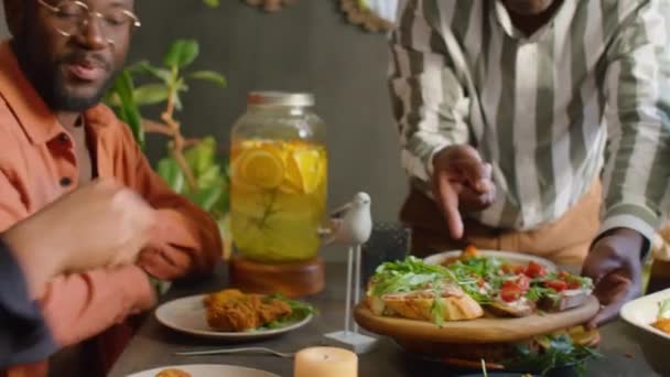 アフリカ系アメリカ人男性は家族と一緒に自宅のディナーパーティーでゲストのためにBruschettasを提供します — ストック動画