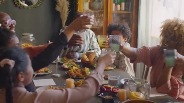 大規模なアフリカ系アメリカ人の家族がトーストでガラスをクリックし 家のディナーパーティーをしながらレモネードを飲む — ストック動画