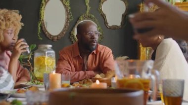 Afro-Amerikalı erkek ve kadınlar aile yemeğinde yemek yerken bir şeyler tartışıyor.
