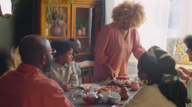 Afro-Amerikalı kadın, aile tatili yemeğinde misafirler için tabakta tatlı ikram ediyor.