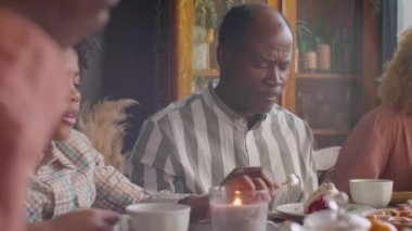 Afrika kökenli Amerikalı anne, baba ve küçük oğlu evde doğum günü yemeğinde pasta yiyip ailesiyle sohbet ediyorlar.