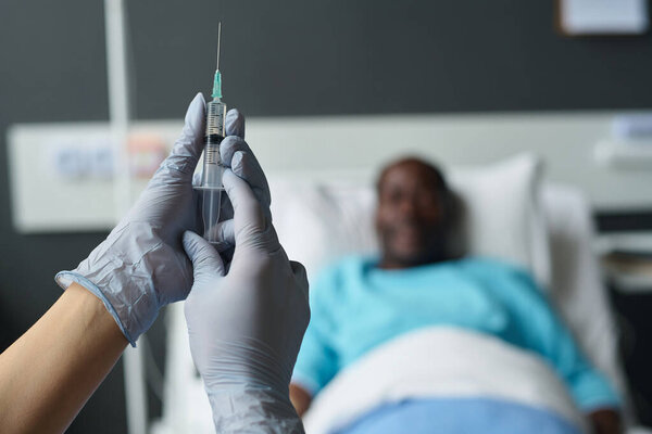 Close-up of nurse in protective gloves holding syringe in hands to make vaccination to patient in hospital