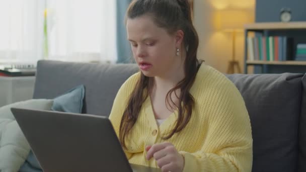 Sendromlu Bir Kızın Evdeki Kanepede Oturup Dizüstü Bilgisayarla Video Konuşması — Stok video
