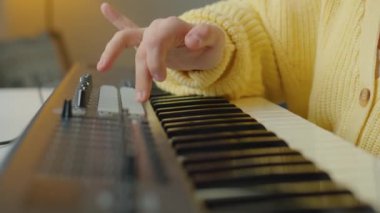 Down sendromlu bir kızın müzik çalmayı öğrenirken sentezleyicideki düğmelere basmasını yakın çekim yap