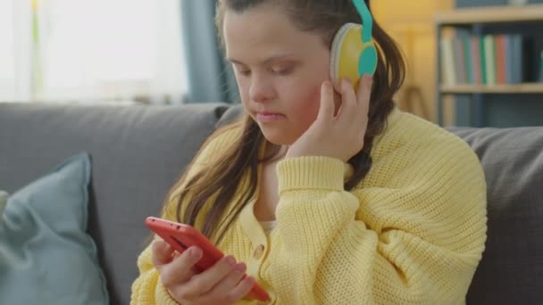 Menina Com Síndrome Sentado Sofá Casa Ouvir Música Smartphone Com — Vídeo de Stock