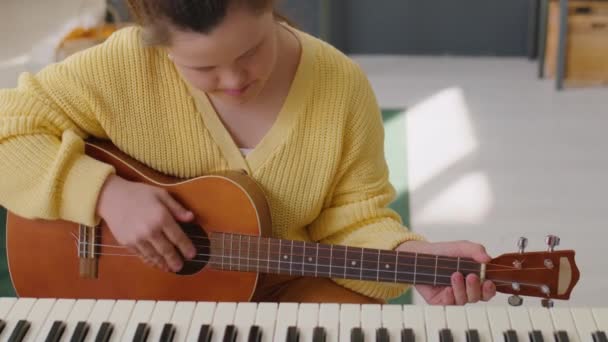 Наклон Снимок Девушки Синдромом Дауна Играющей Гитаре Затем Смотреть Камеру — стоковое видео
