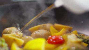 Kızartma tavasına alkol dökerken yakın çekim, sonra ateş yakmak ve alevler içinde yemek pişirmek.