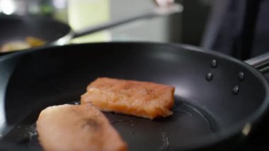 Tavada kızarırken somon filetosuna tuz eklerken yakın çekim