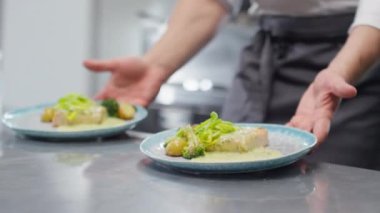 Restaurant mutfağında yemek siparişi verirken iki tabağı metal tabakla hareket ettirirken görüntülenmiş.