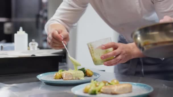 調理場の同僚の協力を得て 皿の上の料理にソースを追加シェフ — ストック動画
