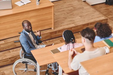 Engelli Afrikalı profesör konferans salonunda bir grup öğrenciye ders veriyor.