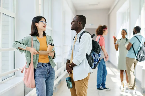 学校の廊下に立っている間 休憩中におしゃべりバックパックを持つ多民族学生 — ストック写真
