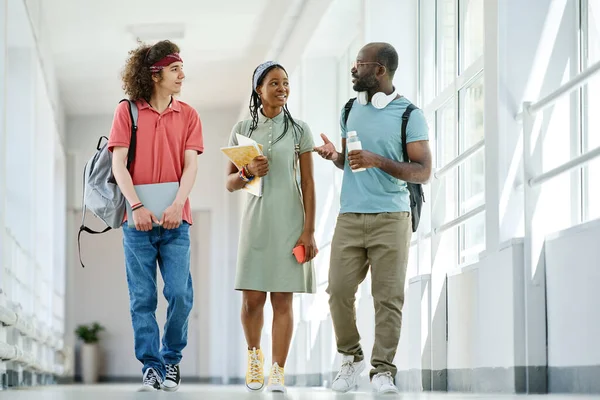 Többnemzetiségű Barátok Beszélgetnek Egymással Miközben Iskola Folyosóján Sétálnak Szünet Alatt — Stock Fotó
