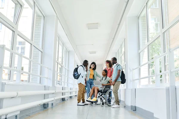 学校の廊下に立ちながら一緒に休憩中にラップトップを使用している学生のグループ — ストック写真