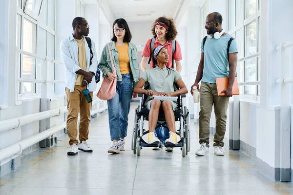 車椅子のアフリカの女の子は学校の廊下を歩いている間に友達とチャット — ストック写真