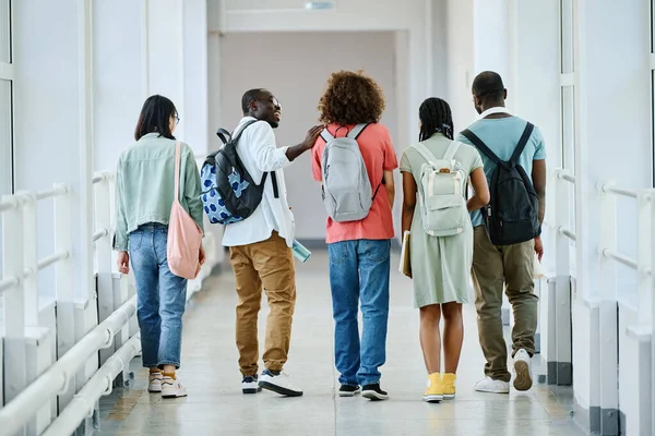 授業後に学校の廊下をバックパックで歩く学生のグループの背面図 — ストック写真