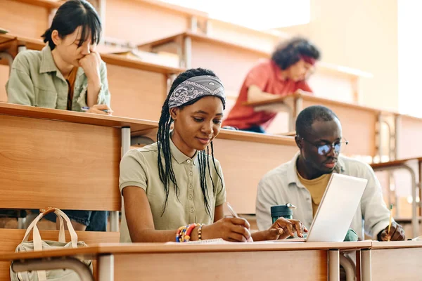 机に座って大学で講義中に勉強する学生のグループ — ストック写真