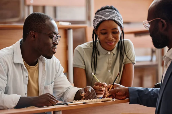 非洲学生坐在大学的课桌前向老师征求意见 — 图库照片