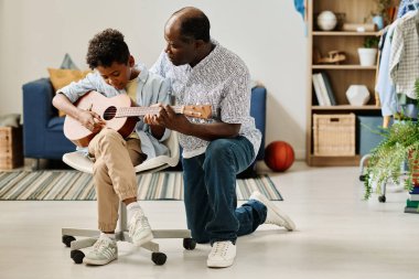 Afrika öğretmeni öğrencisine evde ders sırasında gitar çalmayı öğretiyor.