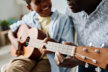 Mutlu Afrikalı küçük çocuğun ev dersinde öğretmeniyle gitar çalmayı öğrenmesi.