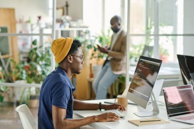 Afrikalı genç programcı ofisinde otururken yeni yazılımlar üzerine kodlar yazmaya odaklanıyor.