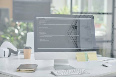 Ofisteki cam duvarın arkasında bilgisayarı olan programcının iş yerinin yakın çekimi.