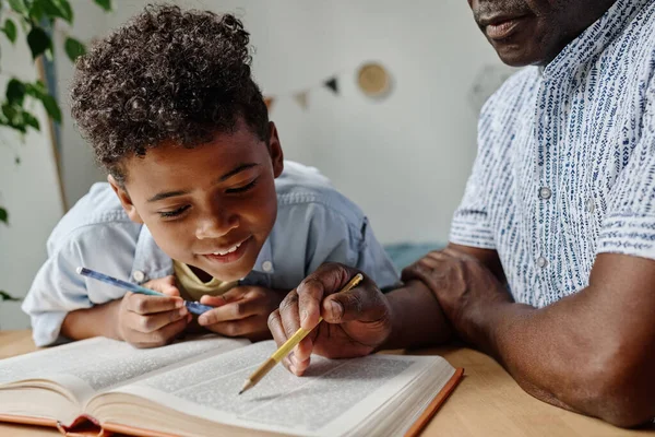 アフリカの少年は家庭教育中にテーブルで先生と一緒に本を読んでいます — ストック写真