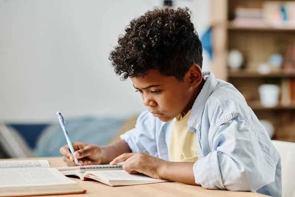 アフリカの少年は机の上に座ってノートを作る宿題をしています — ストック写真