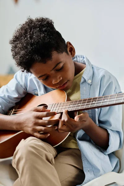 stock image African boy examining the notes on guitar while he learning to play musical instrument at lesson