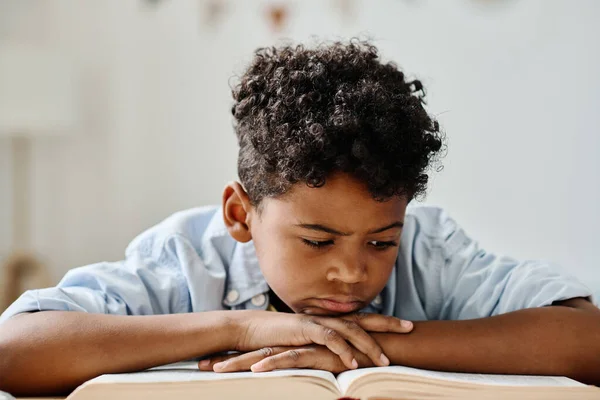 Серьезный Африканский Мальчик Сосредоточенный Чтении Книги Дома Лицензионные Стоковые Фото