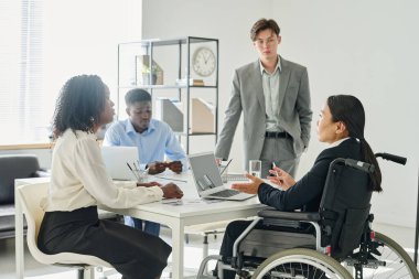 İş adamları iş toplantısı sırasında tekerlekli sandalyedeki iş liderleriyle konuşuyor.