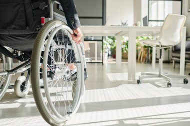 Ofiste çalışırken tekerlekli sandalyede oturan engelli bir ofis çalışanının yakın çekimi.