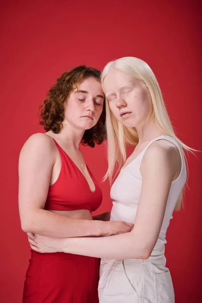 Πορτρέτο Δύο Κοριτσιών Ασυνήθιστες Εμφανίσεις Αγκαλιάζει Πάνω Από Κόκκινο Φόντο — Φωτογραφία Αρχείου