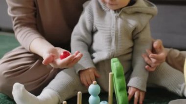 Bebeğin annesinin dizlerinin üstüne çöküp onunla ve ağabeyiyle oturma odasında oyuncaklarla oynarken çekimini yap.