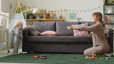 Annem çocuk odasında yerde oturuyor ve çocuk evde ilk adımlarını atarken ona sesleniyor.