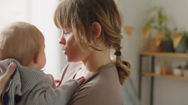 Sevgi dolu anne kucağında tatlı bir bebekle evde çocuk odasında