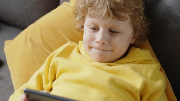 Vit Liten Pojke Som Ligger Soffan Hemma Spelar Spel Digital — Stockvideo