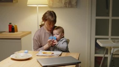 Bebeğim, mutfak masasında sevgili annesiyle otururken şişeden su içip poğaça yiyor.