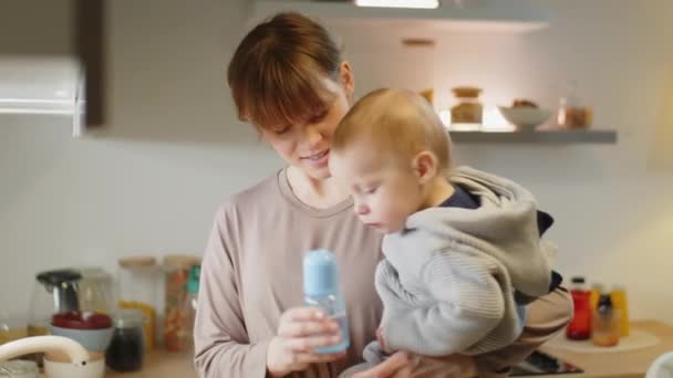 Веселая Мать Держащая Малыша Руках Давая Ему Бутылочку Водой Кепку — стоковое видео
