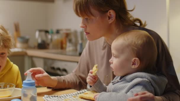Мама Сидит Маленьким Мальчиком Кухонным Столом Разговаривает Старшим Сыном Младшего — стоковое видео