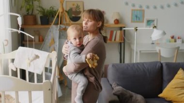 Sevimli çocuk oyuncaklarla oynarken sevgi dolu anne onu çocuk odasında kollarına aldı.