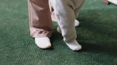 Bebeğin bacaklarının düşük kesiminde annesinin yardımıyla ilk adımları atıyor.